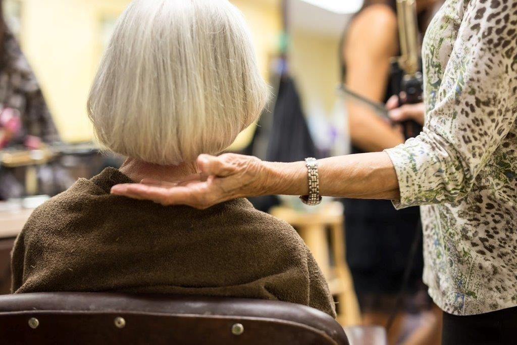 A woman is getting her hair cut by a hairdresser in a salon.