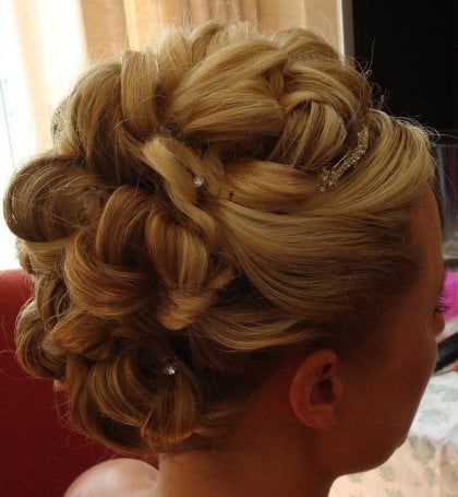 A woman is wearing her hair in a bun with a braid and pearls.