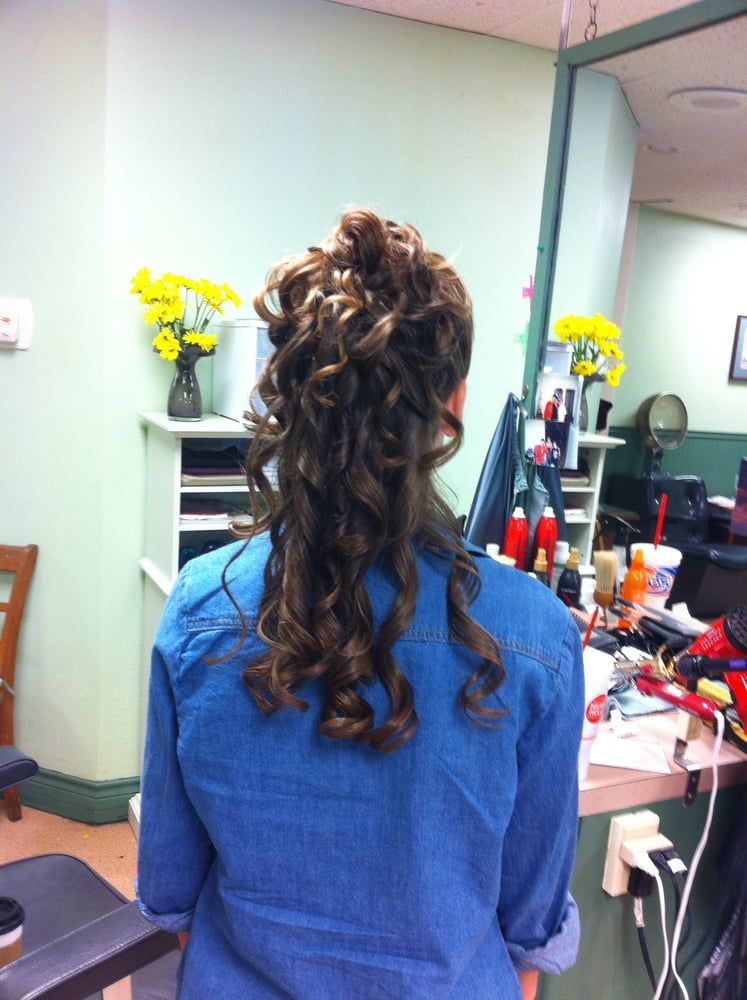 A woman in a blue shirt has her hair in a half up half down ponytail