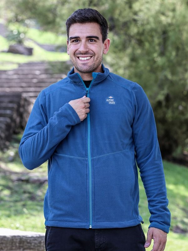 Un hombre lleva una chaqueta de polar azul y sonríe.