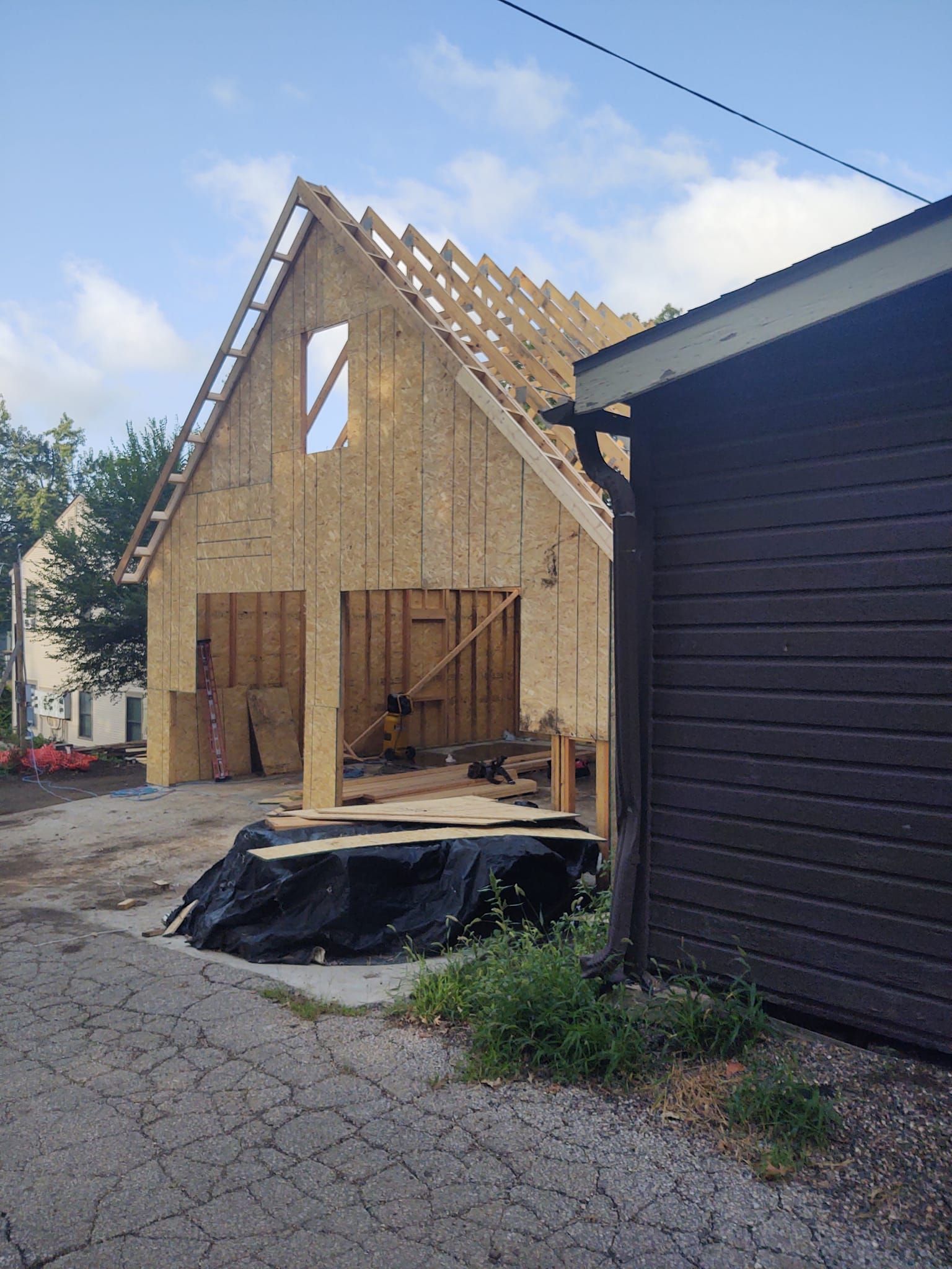 A house is being built on a dirt road next to a garage.