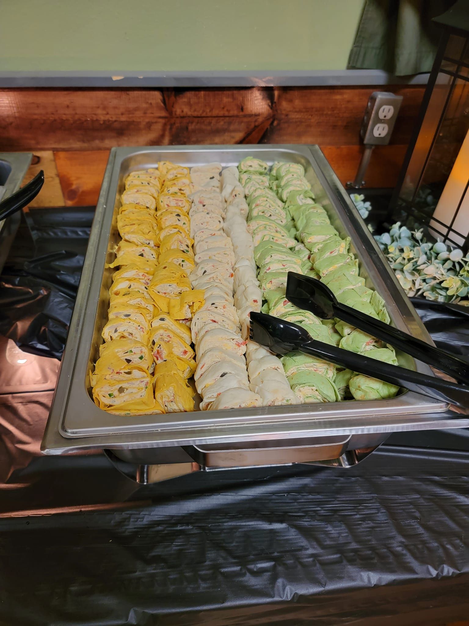 A tray of food with tongs on a table.