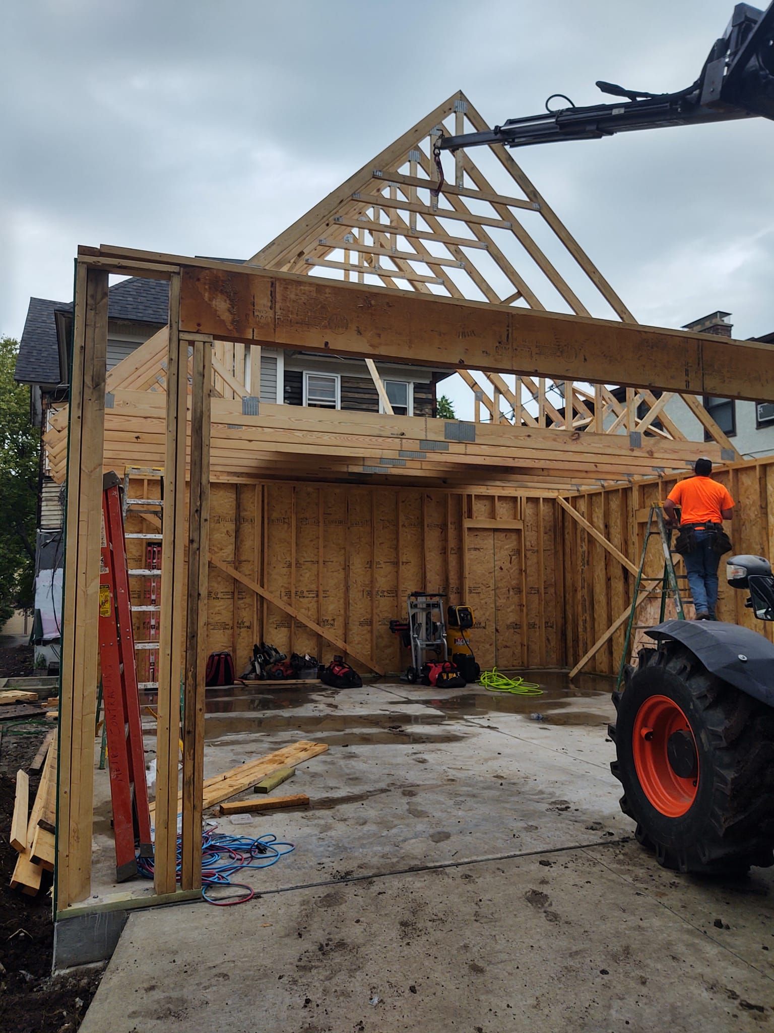 A man is standing on a ladder in front of a building under construction.
