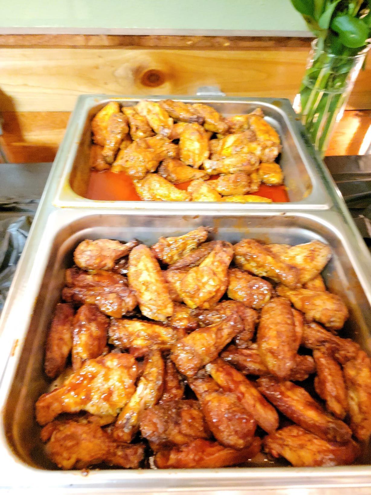 Two trays of chicken wings are sitting on a buffet table.