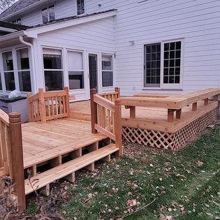 A wooden deck is sitting in front of a white house.