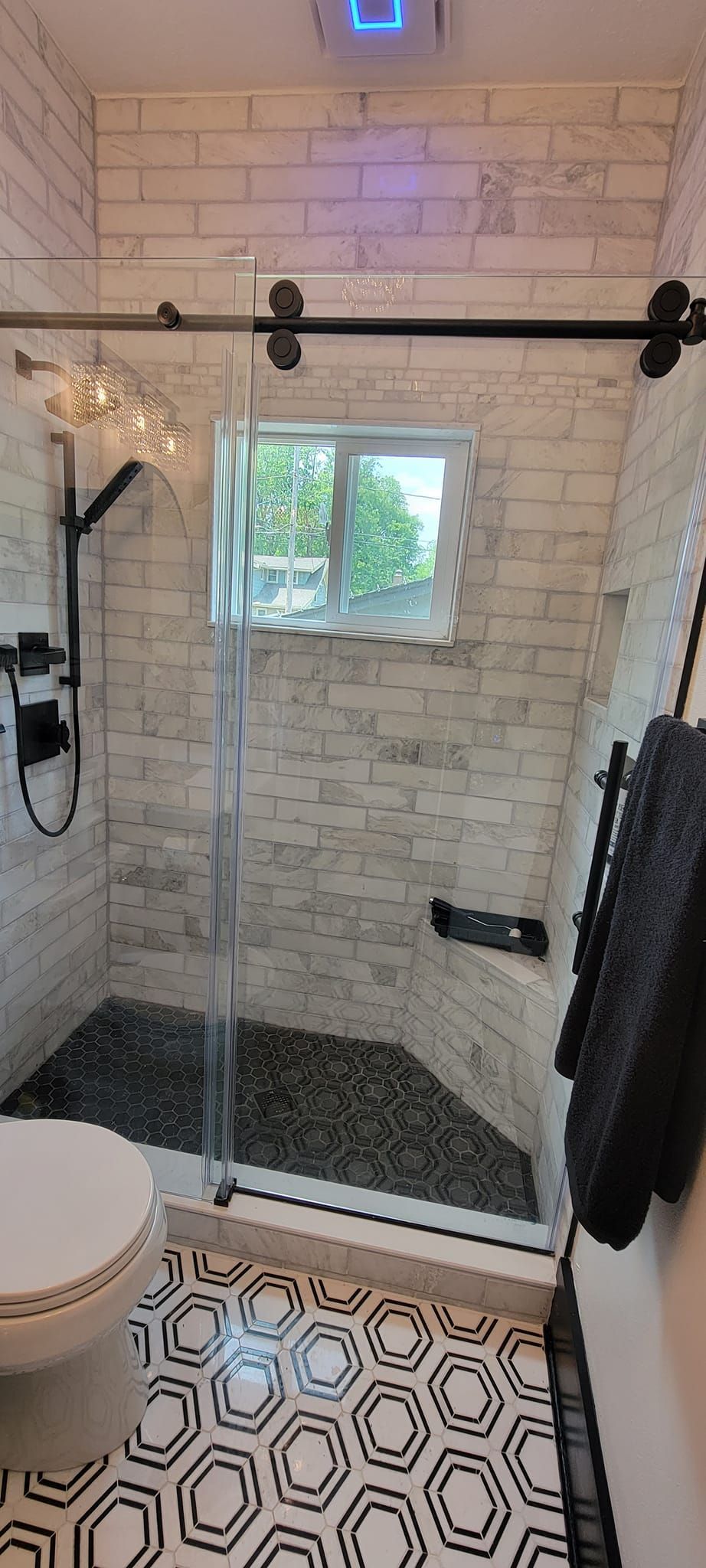 A bathroom with a toilet , shower , and window.