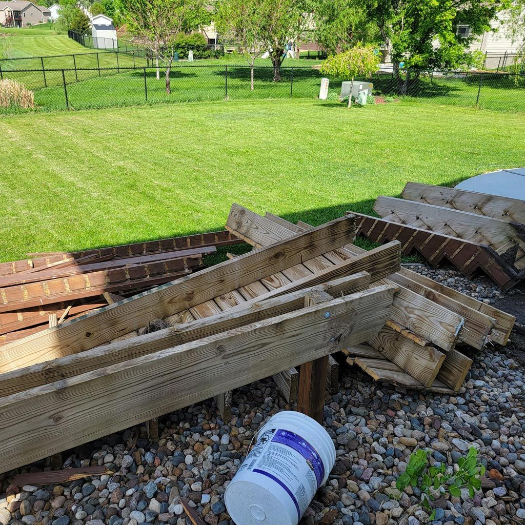 A pile of wood is sitting on top of a pile of gravel in a yard.