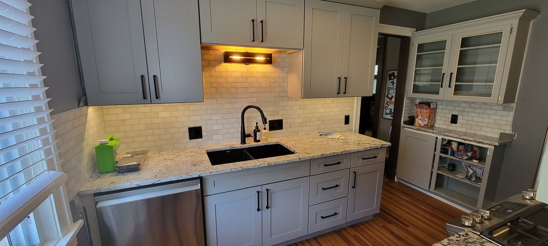 A kitchen with white cabinets , granite counter tops , stainless steel appliances and a sink.