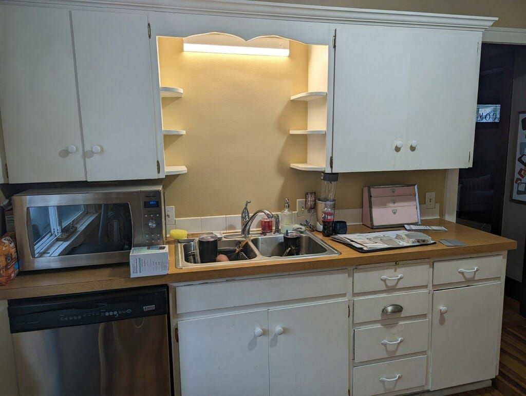 A kitchen with white cabinets , a sink , a microwave , and a dishwasher.