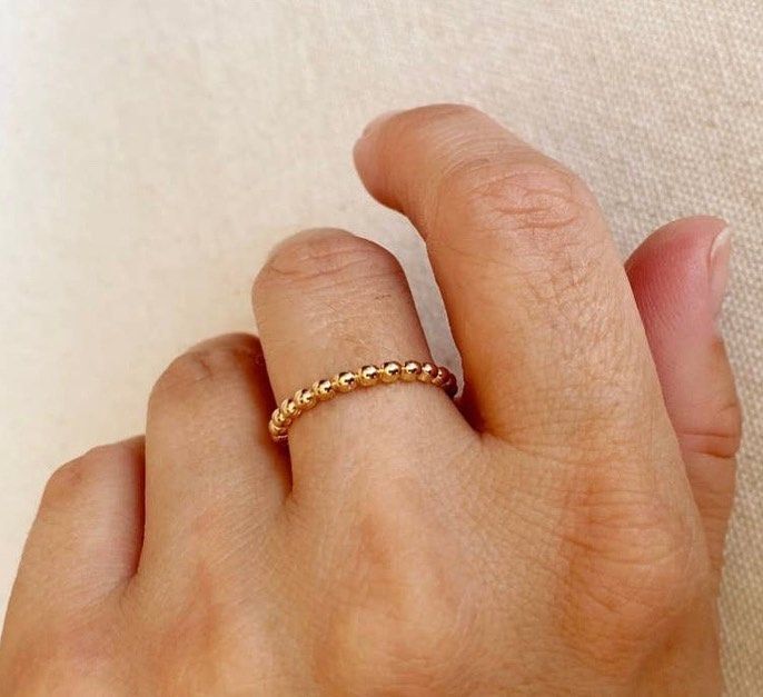 A person wearing a gold ring on their finger