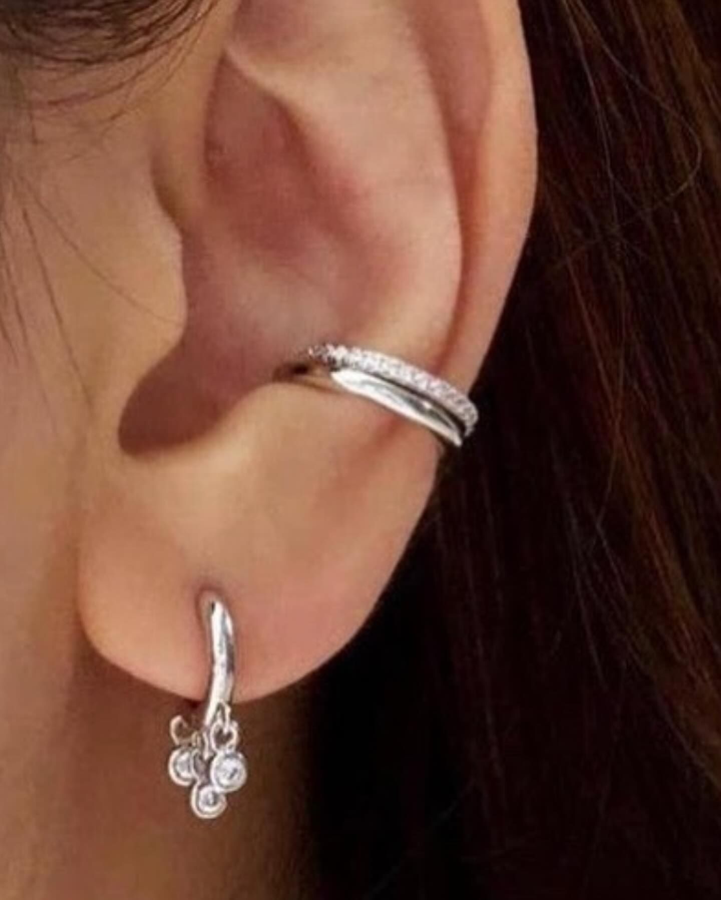 A close up of a woman 's ear with earrings and a ear cuff.