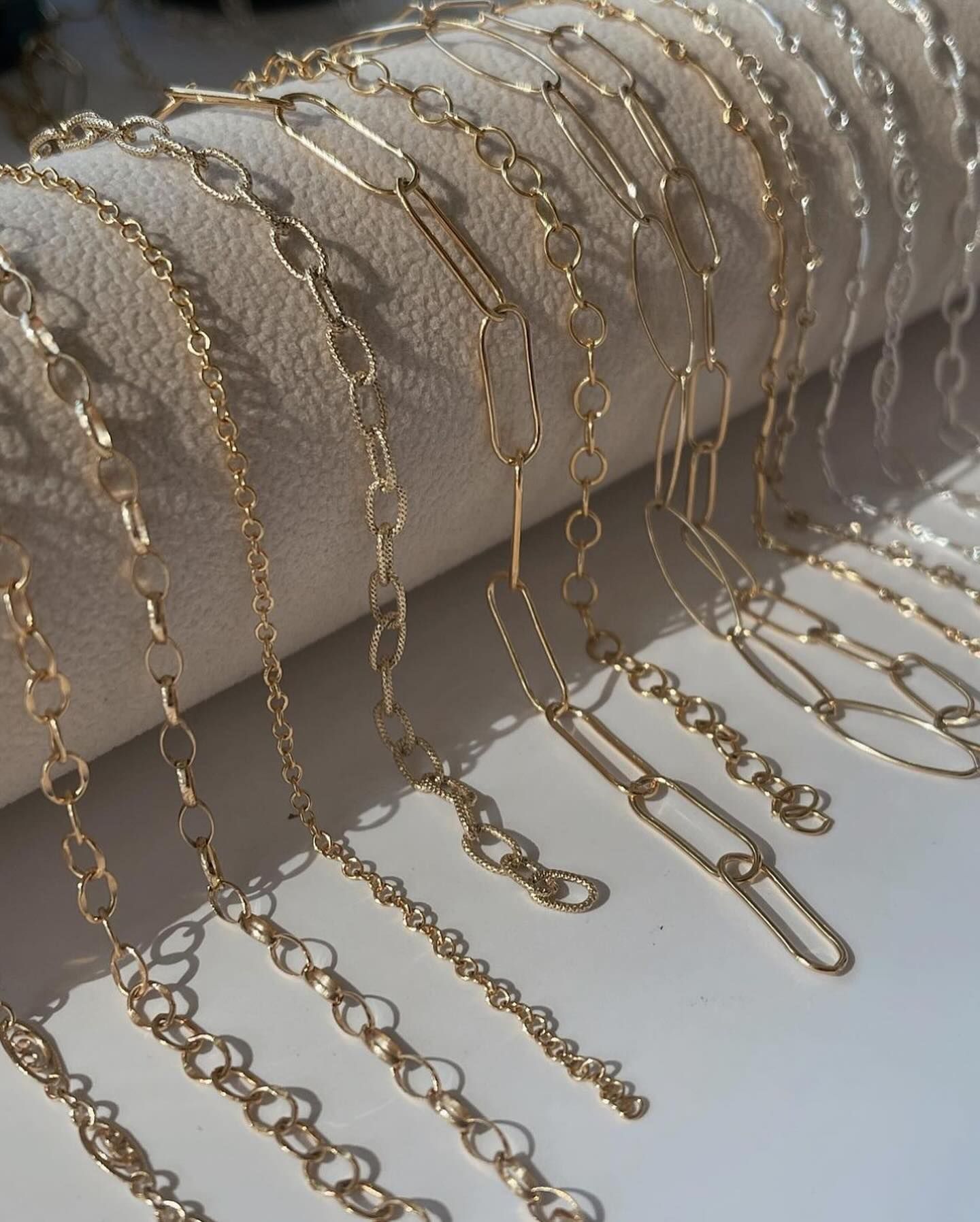 A bunch of gold chains are laying on a white surface