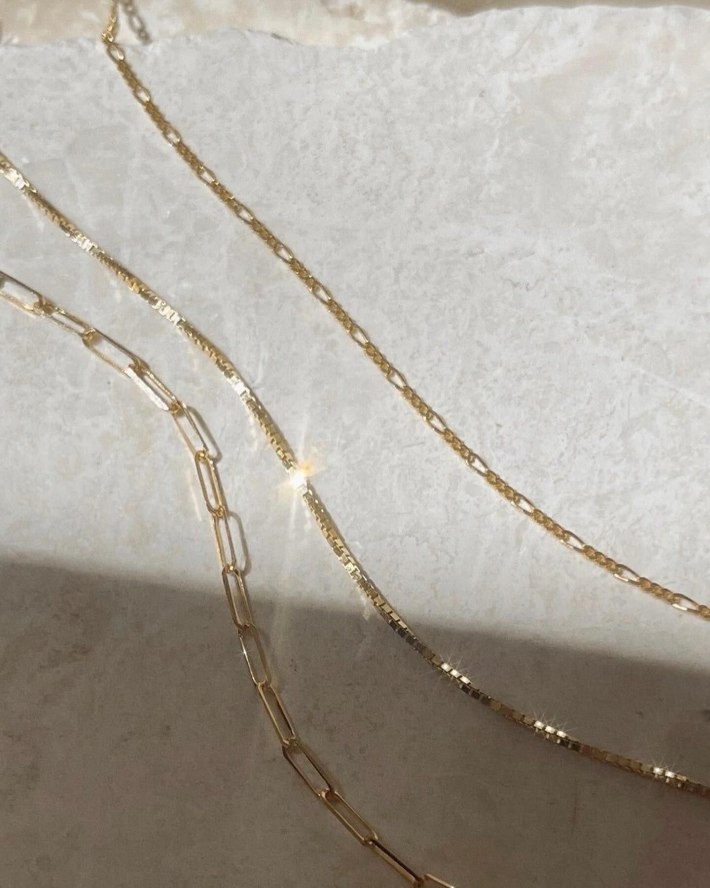 A close up of three gold chains on a white surface