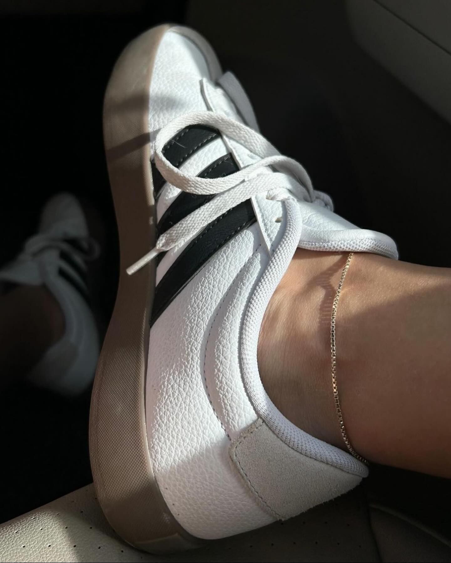 A person wearing a pair of white and black adidas shoes