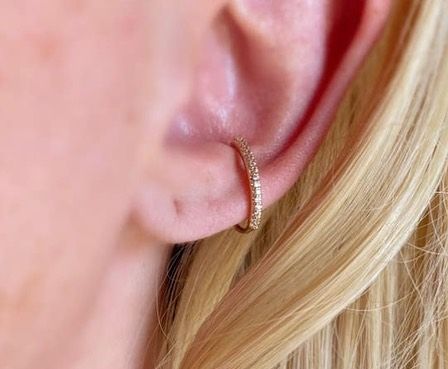 A close up of a woman 's ear with a hoop earring.
