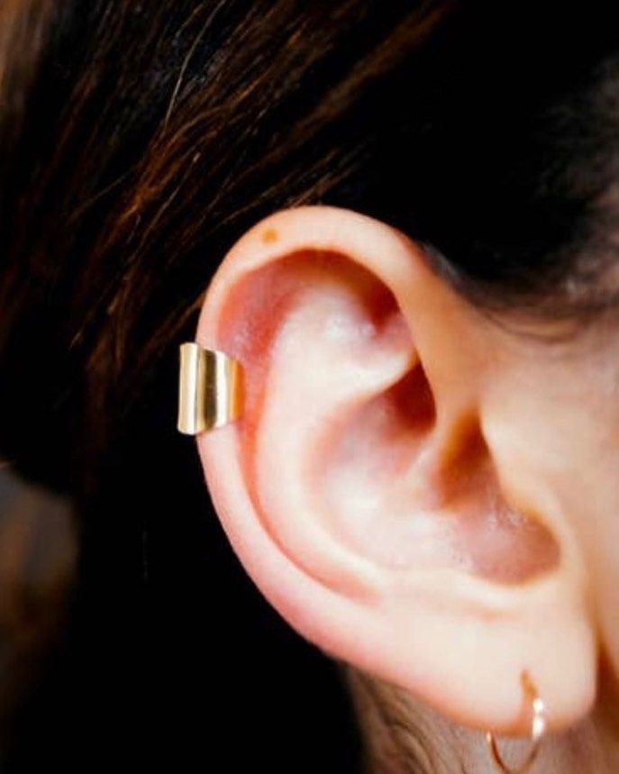 A close up of a woman 's ear with a gold ear cuff
