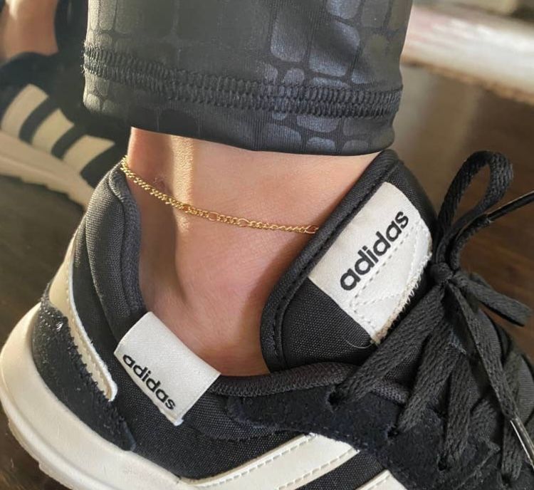 A person wearing a black and white adidas shoe