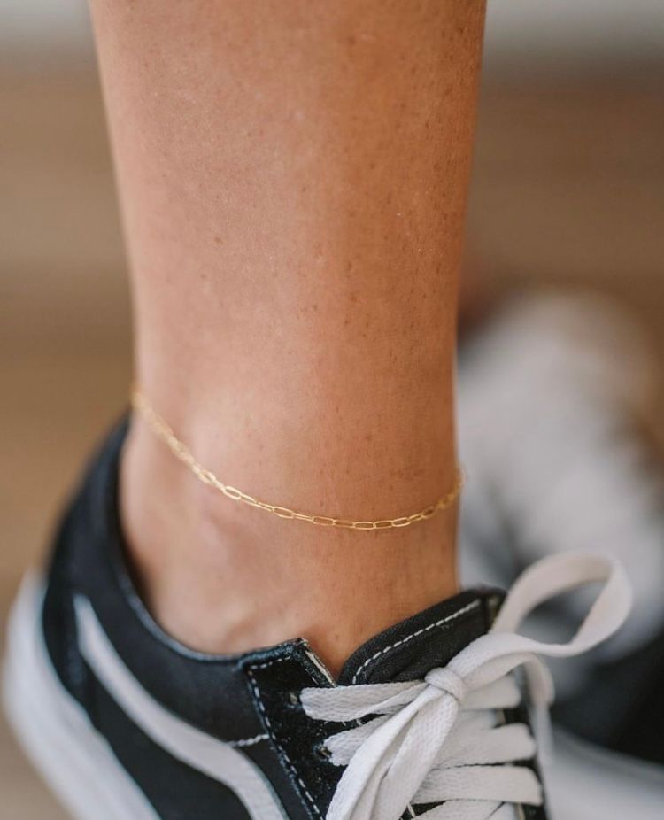 A close up of a person 's ankle wearing a gold anklet