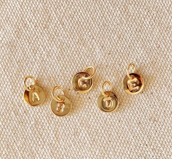 A group of gold pendants with letters on them are sitting on a table.