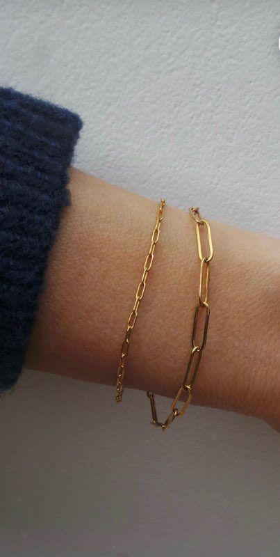 A person is wearing two gold bracelets on their wrist.