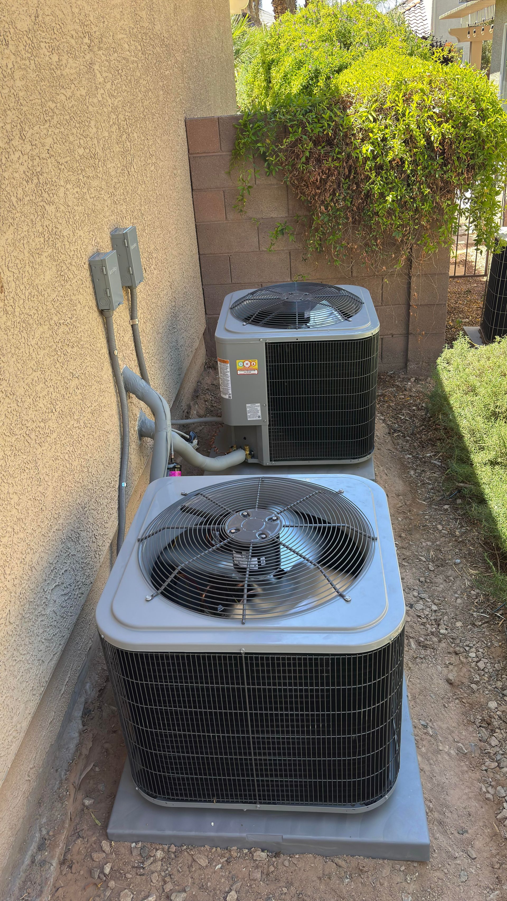 A large air conditioner is sitting on a sidewalk next to a wall.