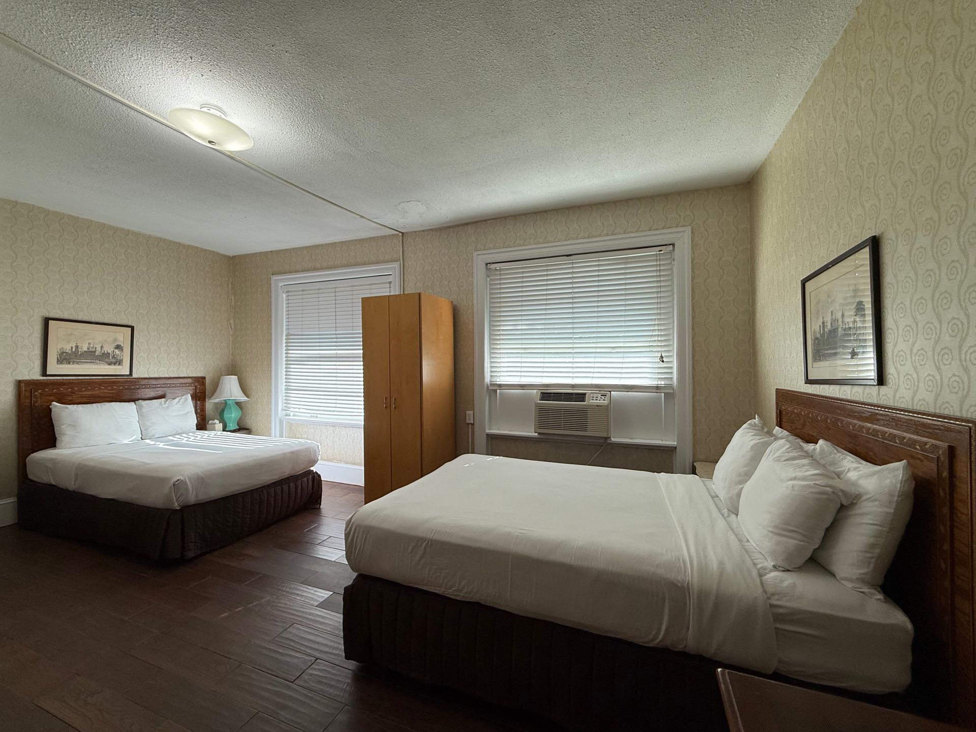 Hotel room with two double beds, window, and wood furniture.