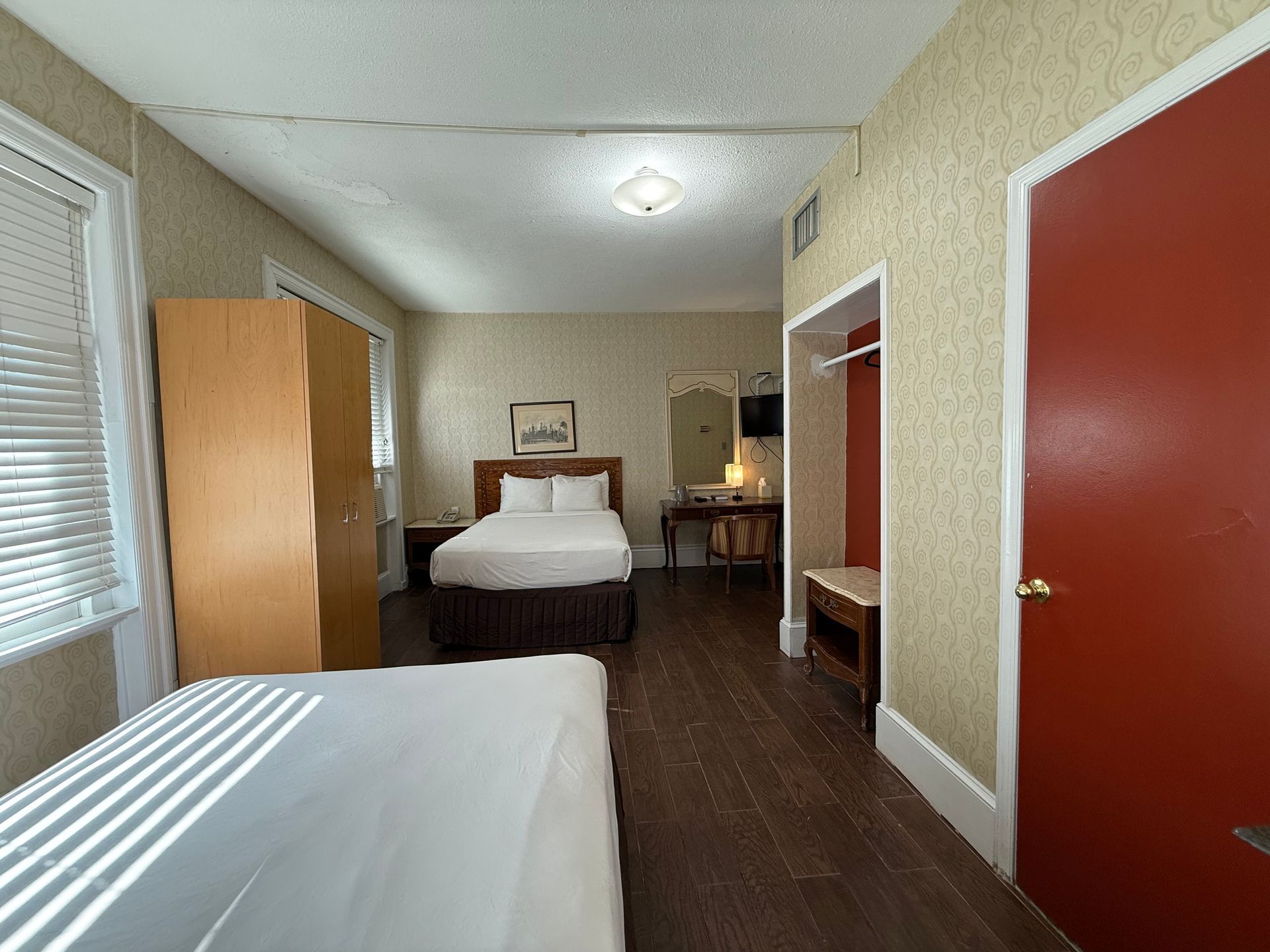 Hotel room with two beds, a wardrobe, and a red door.