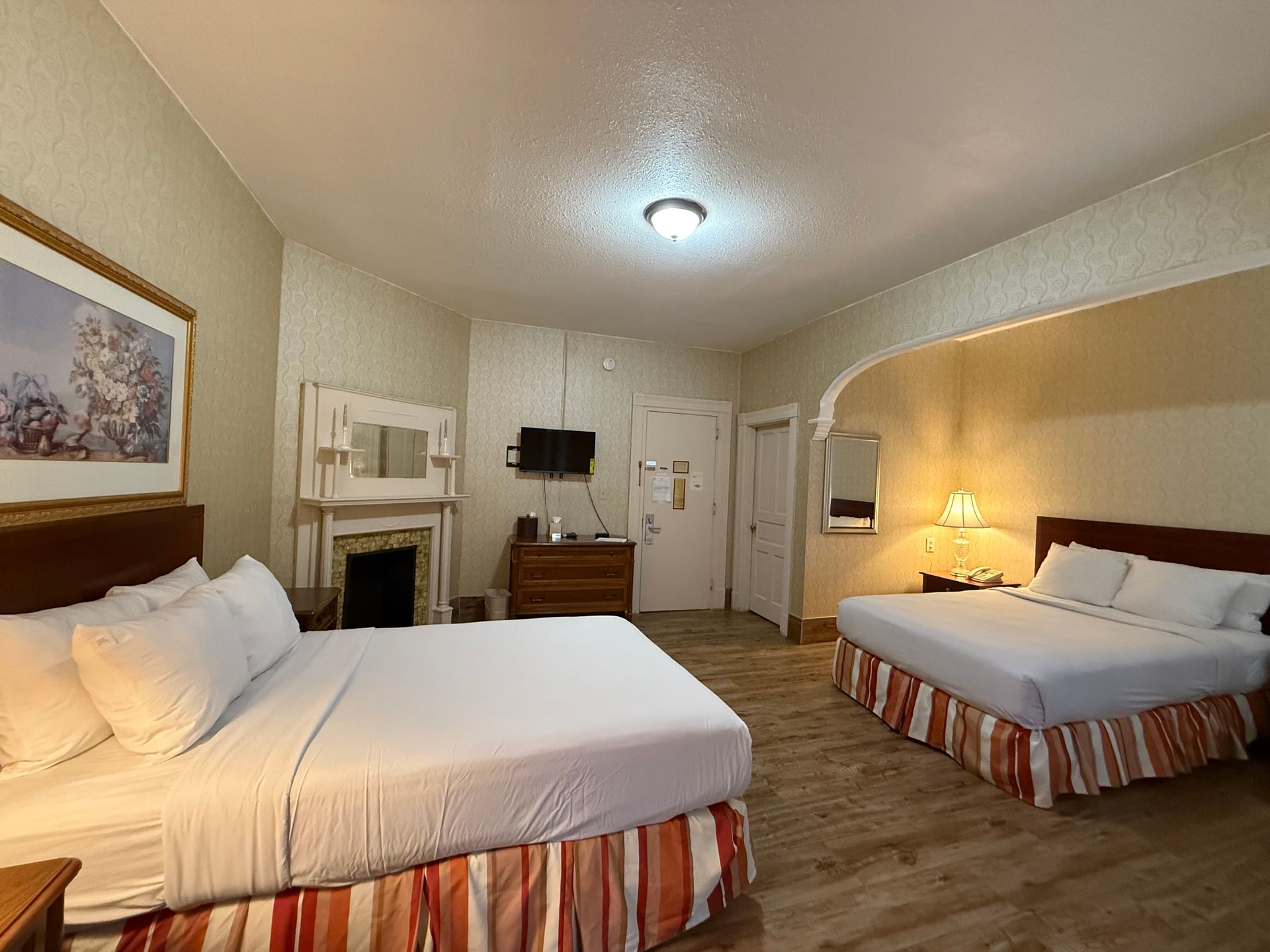 Hotel room with two queen beds, a fireplace, and a small television.