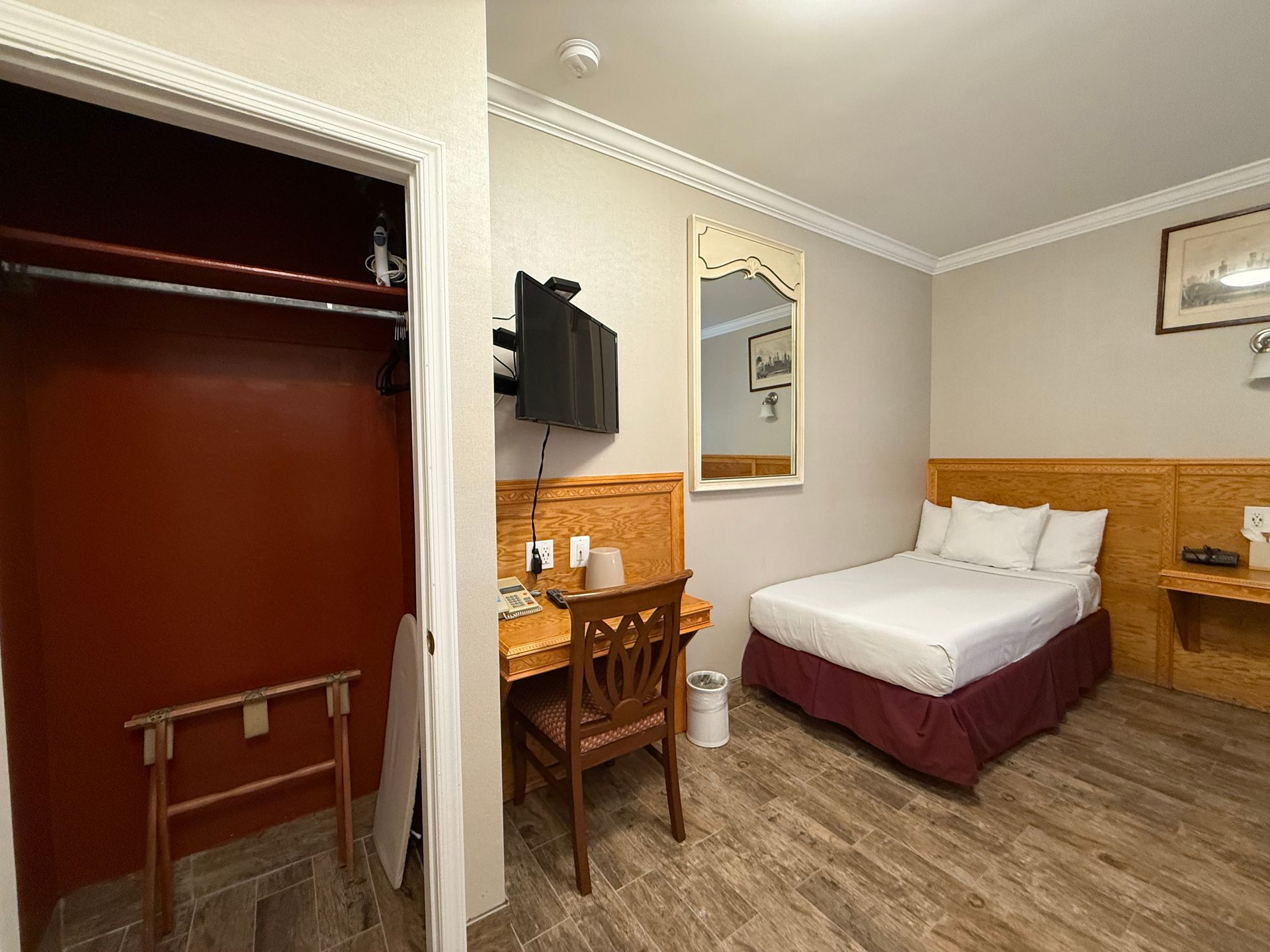 Hotel room with a bed, desk, closet, and mounted TV.