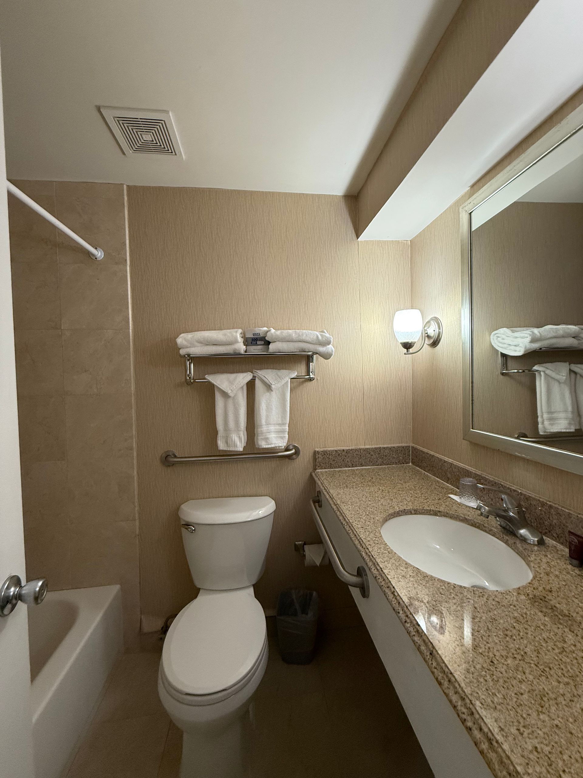 Bathroom with a toilet, sink, mirror, and a shower/tub. Beige walls and counter.