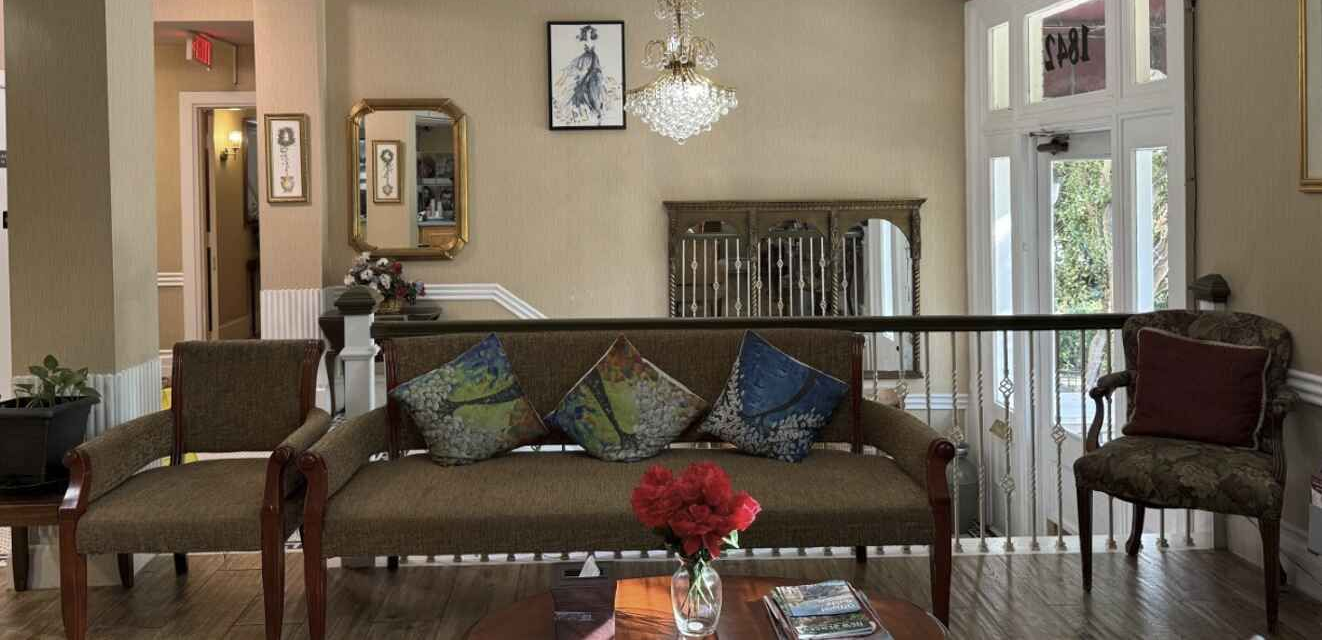 Lobby with a seated area, coffee station, and reception desk. Wall displays feature black and white portraits.