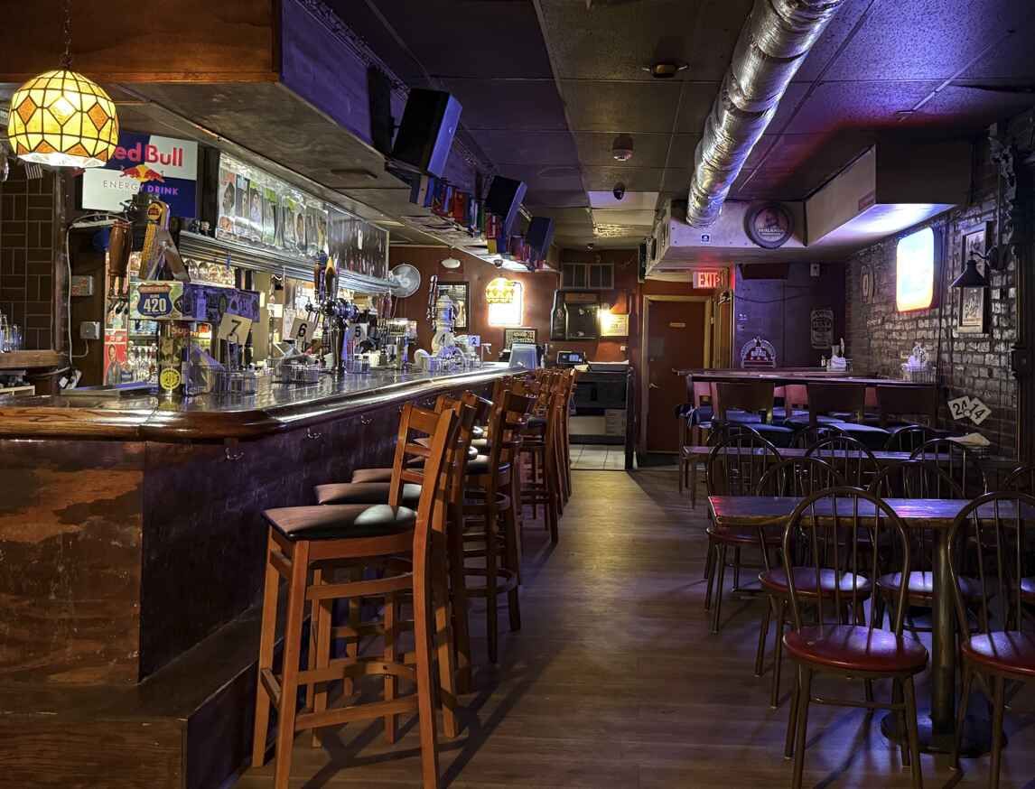 Building with arched windows, surrounded by colorful flowers and greenery, behind a decorative white fence.