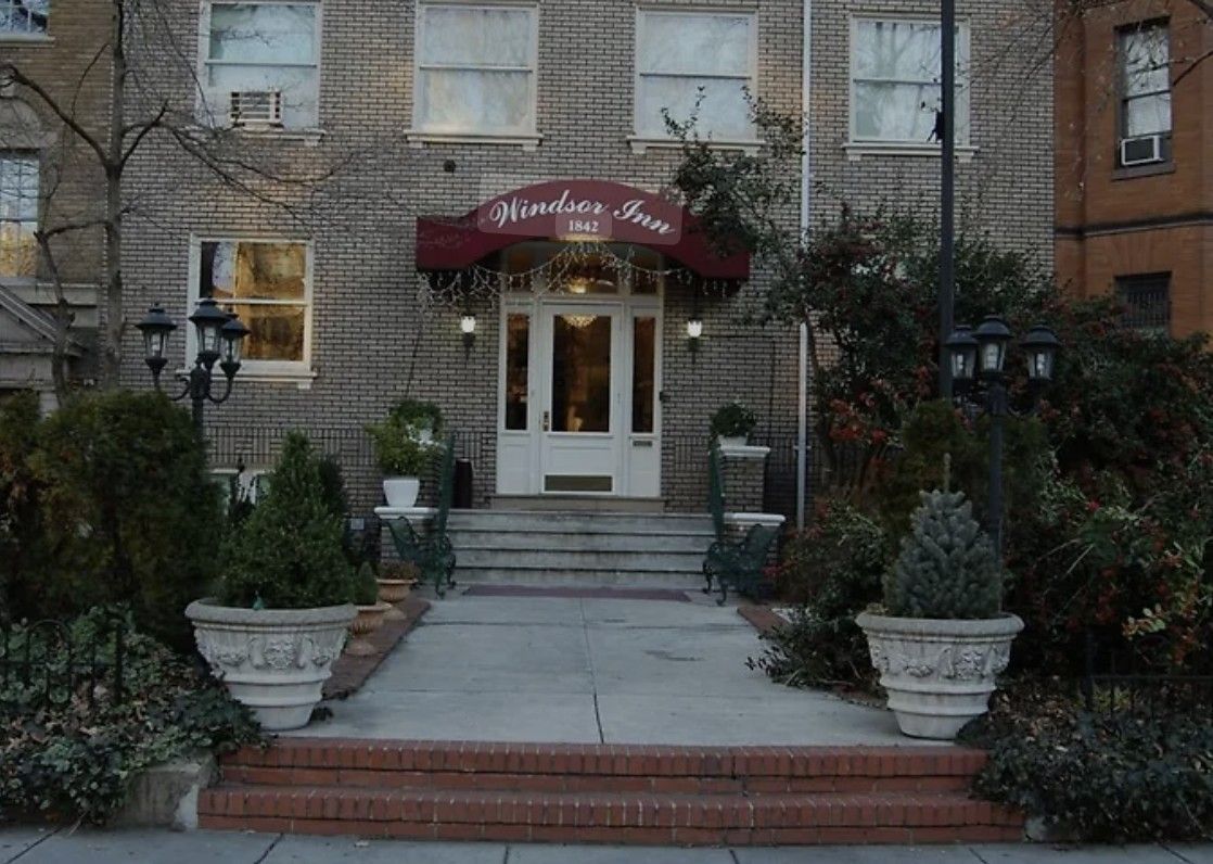 Entrance to the Hinsdale Inn, a three-story brick building with steps leading to a door under a burgundy awning.