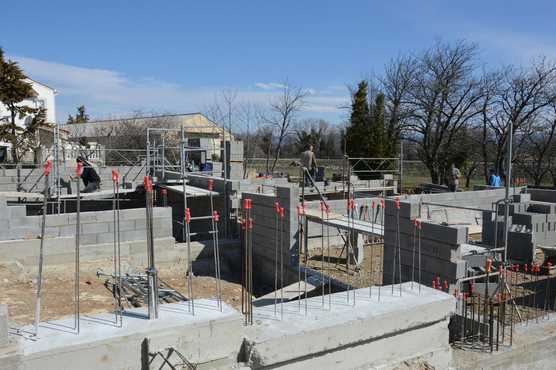 Construction site: concrete blocks and scaffolding with a person working; sunny, outdoors.