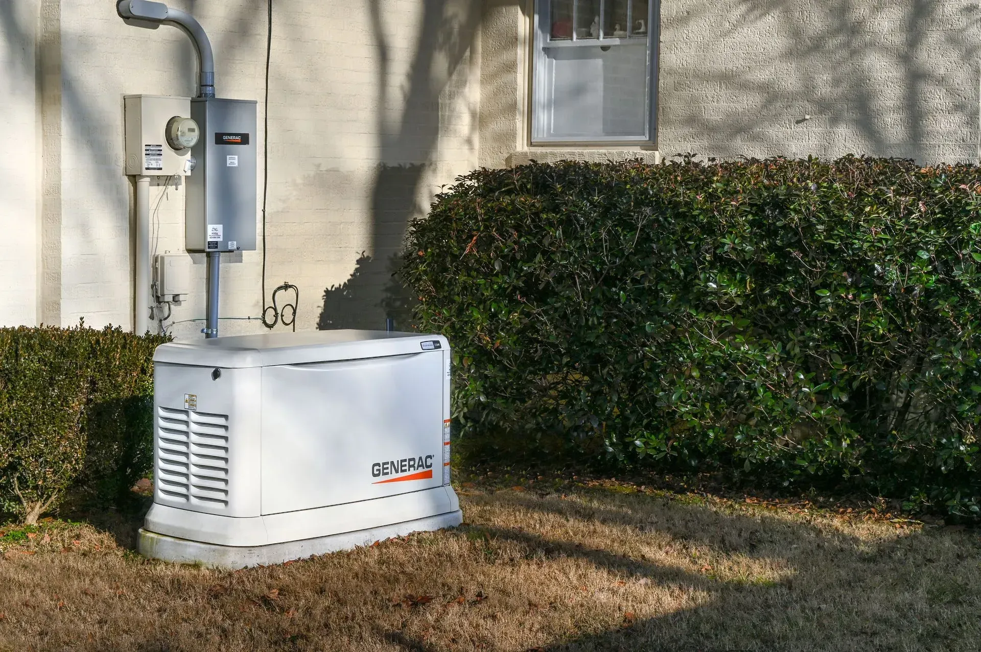 A white generator is sitting in the grass in front of a house