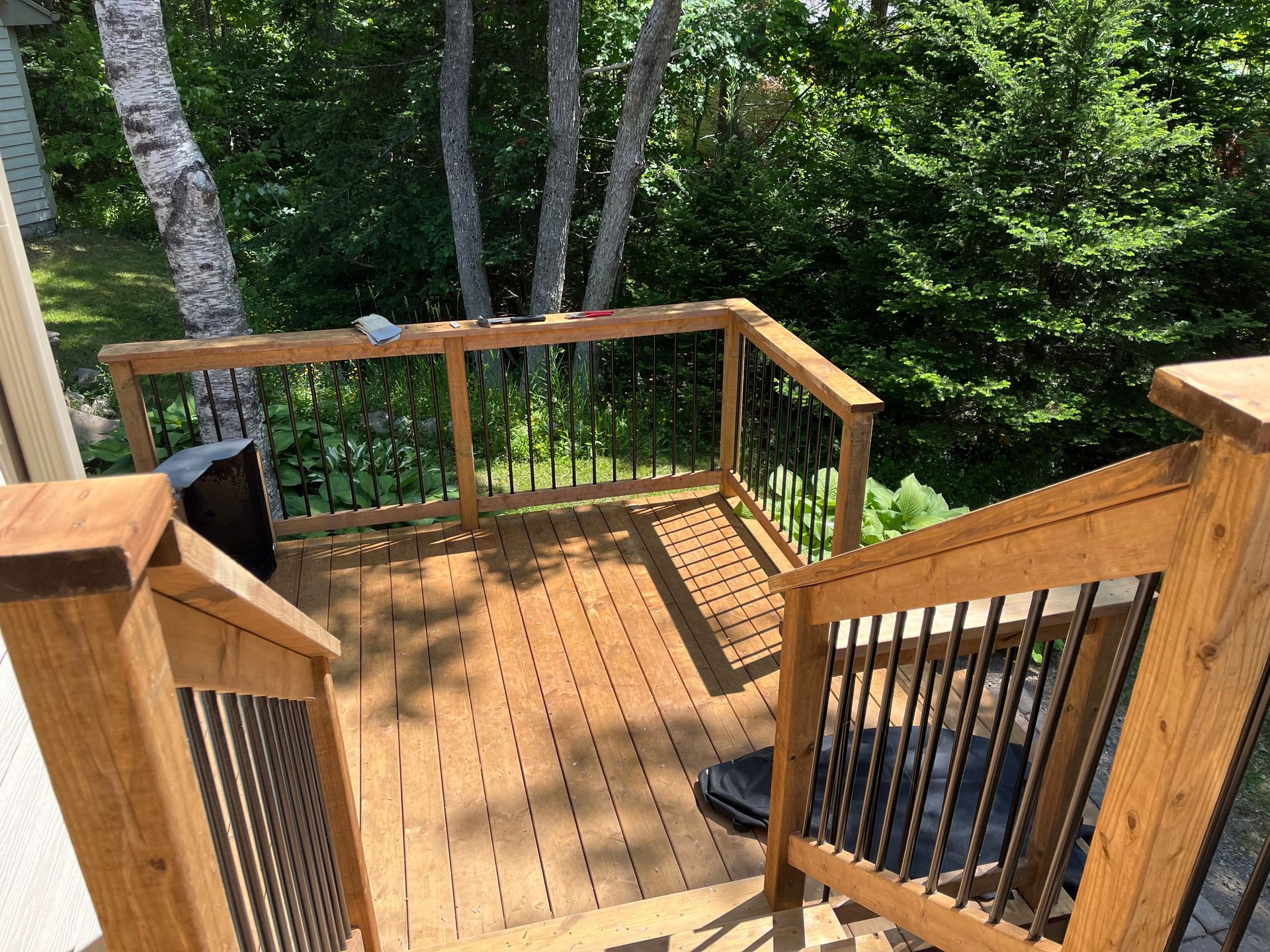 stairs of a deck in a yard surrounded by tress