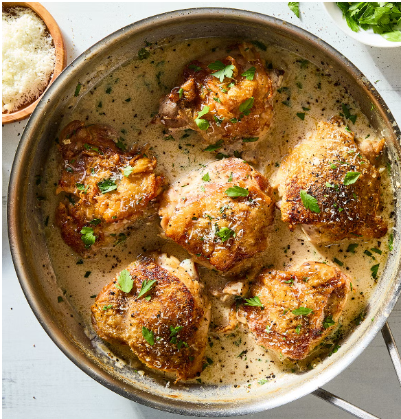 A pan filled with chicken thighs in a creamy sauce.