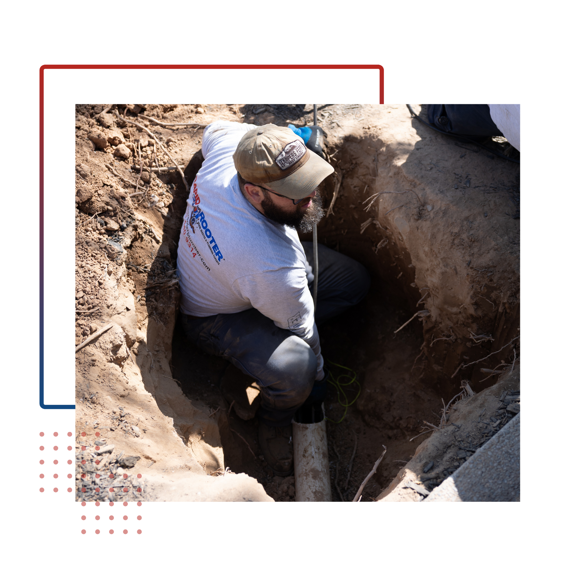 A man is kneeling down in a hole holding a pipe.