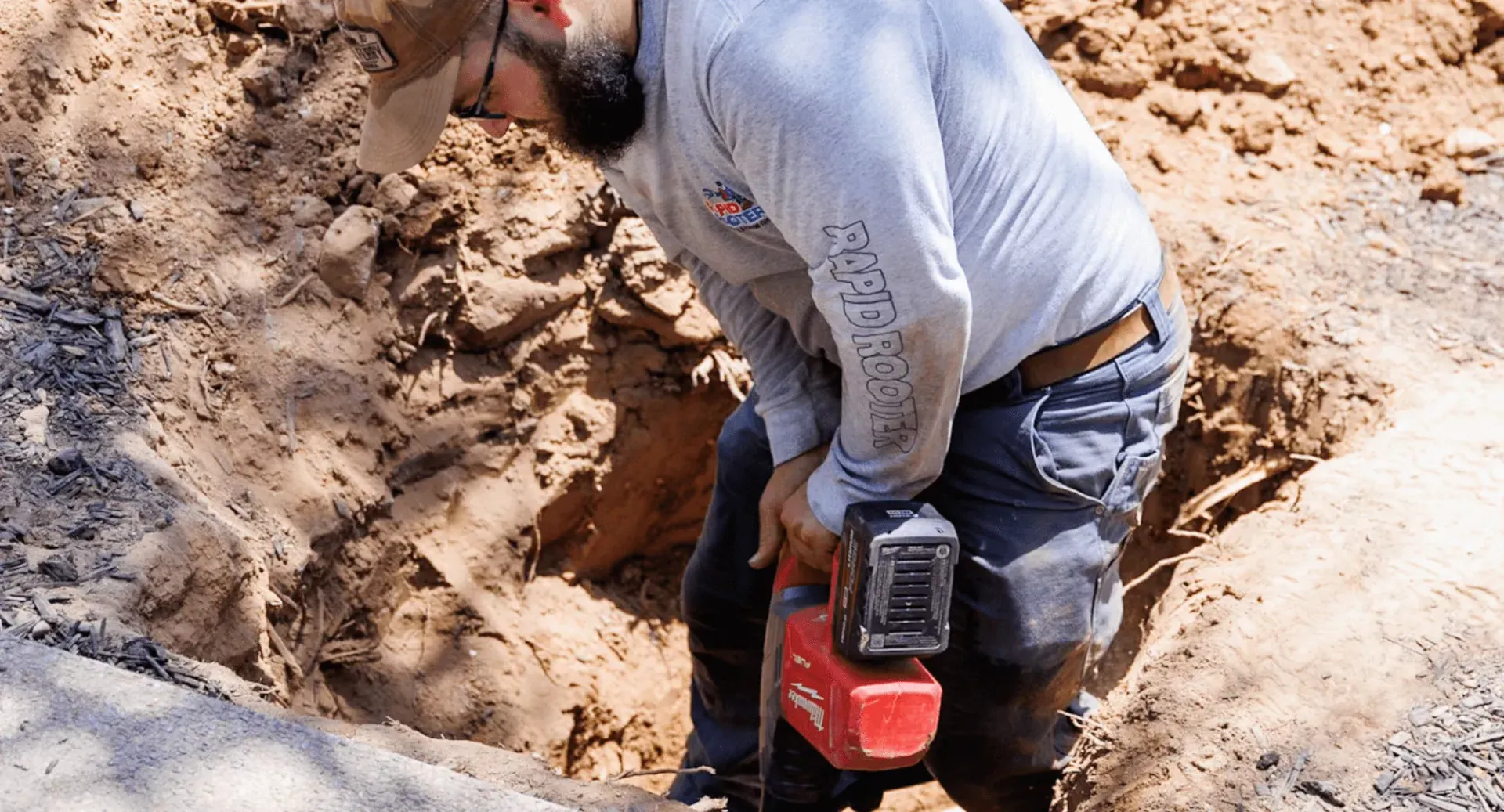 A man is using a hammer to dig a hole in the ground.