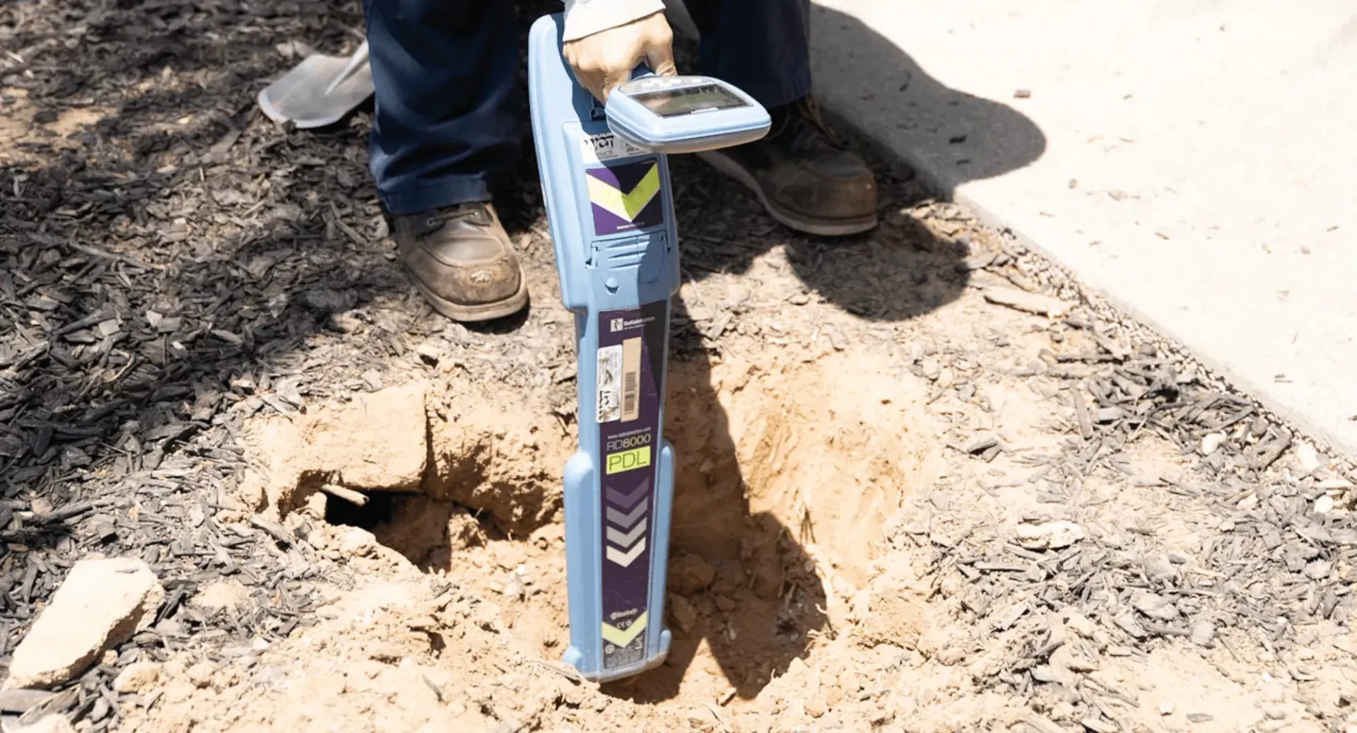 A person is using a metal detector to find a hole in the ground.