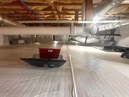 The ceiling of a basement with a lot of pipes and insulation.
