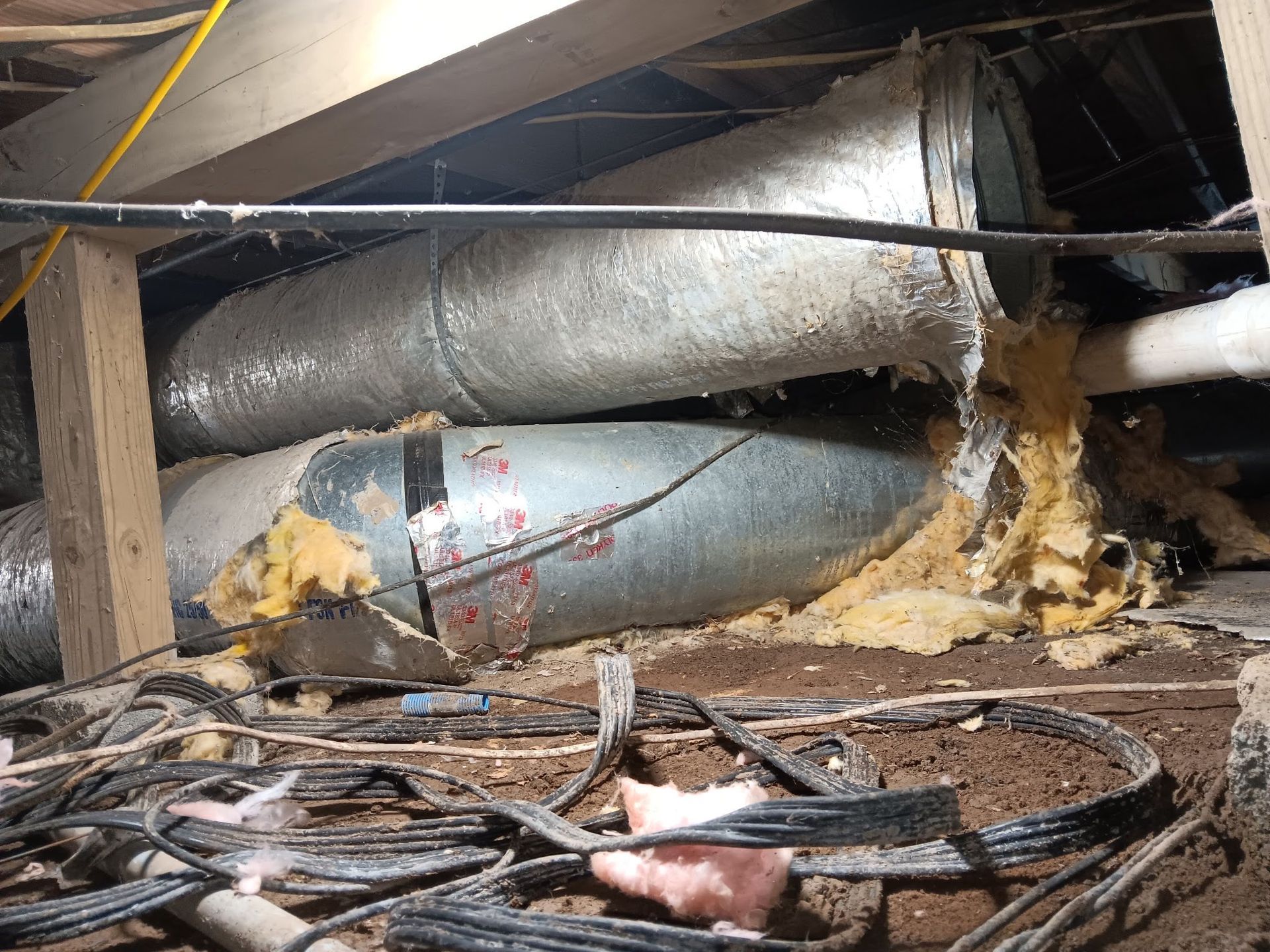 Damaged HVAC ductwork in crawl space. Metal ducting is crushed and insulation is exposed.