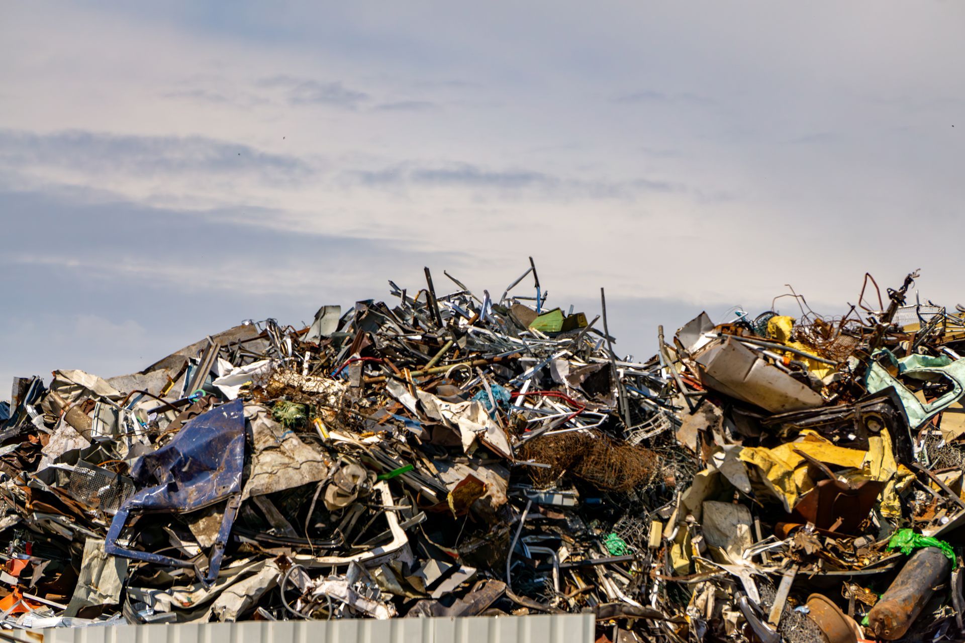 Large pile of twisted and crushed scrap metal under a clear sky.