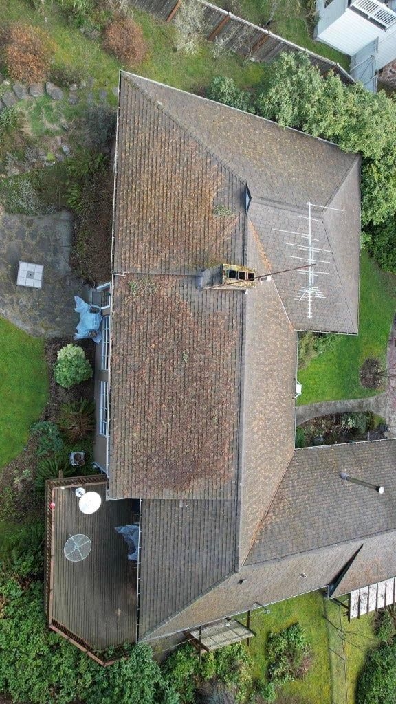 Overhead view of a house with a brown roof, deck, and surrounding greenery.