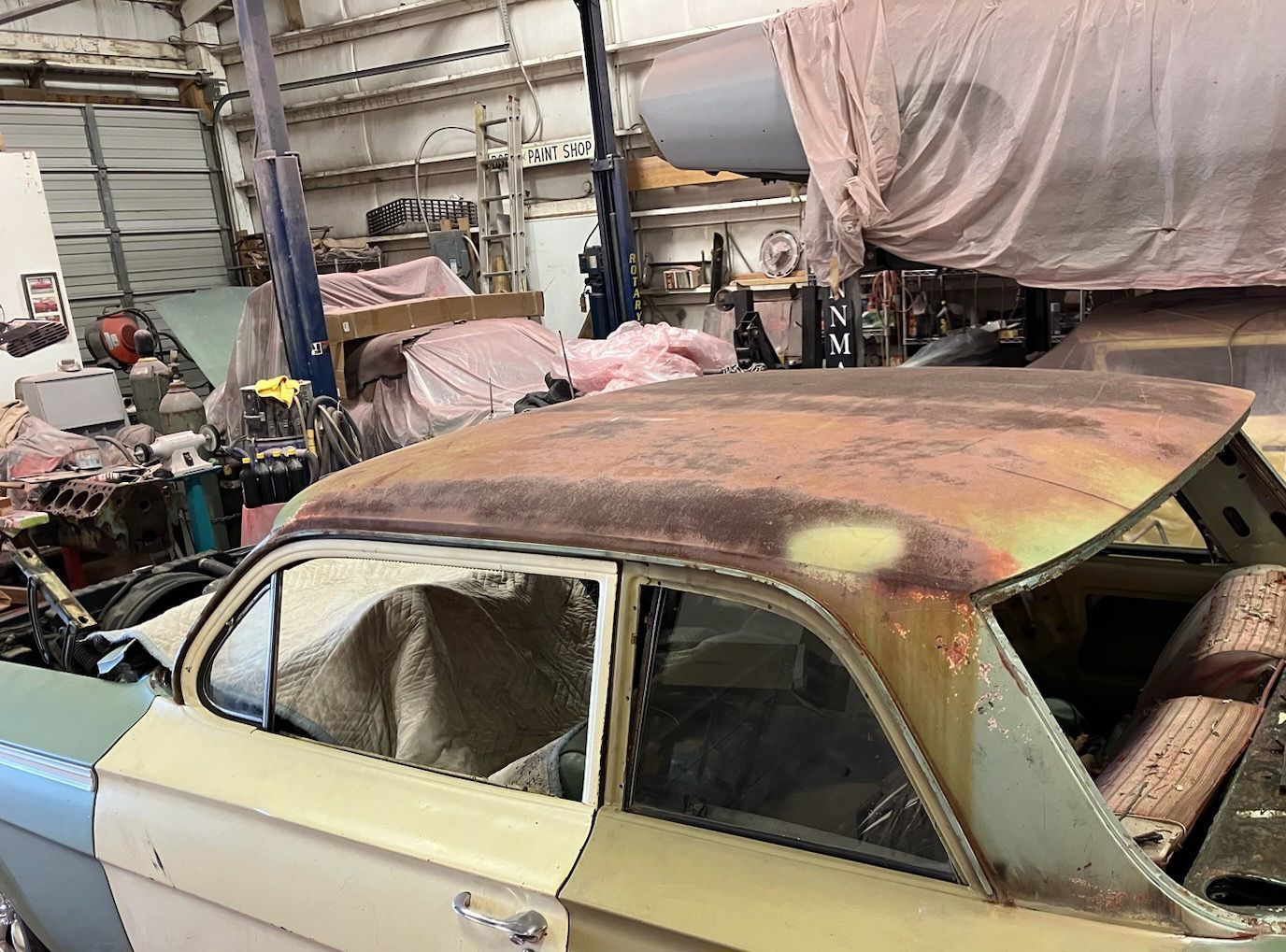 Rusty vintage car roof in a cluttered garage.