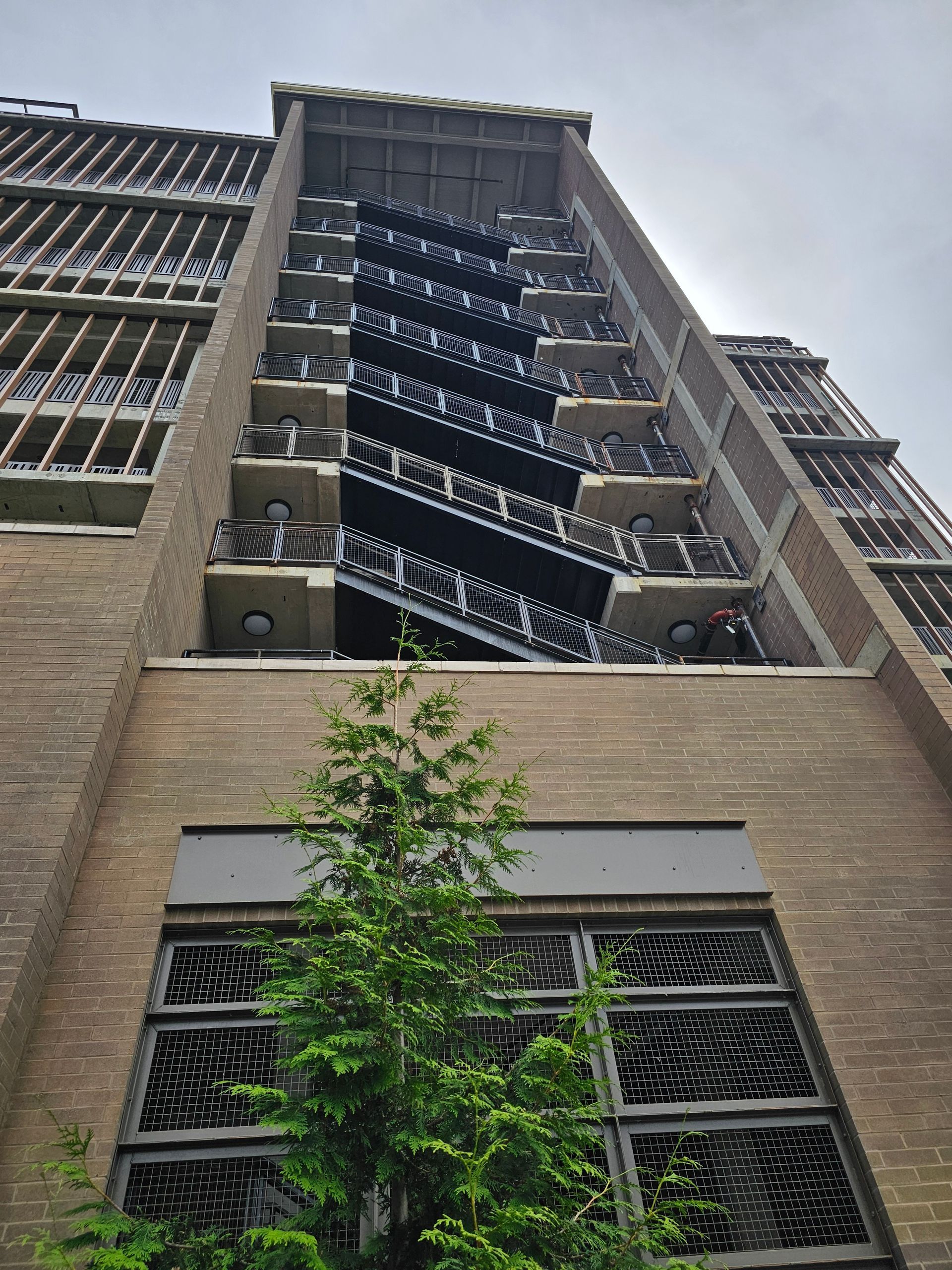 Brick building with exterior metal fire escape, tree in front.