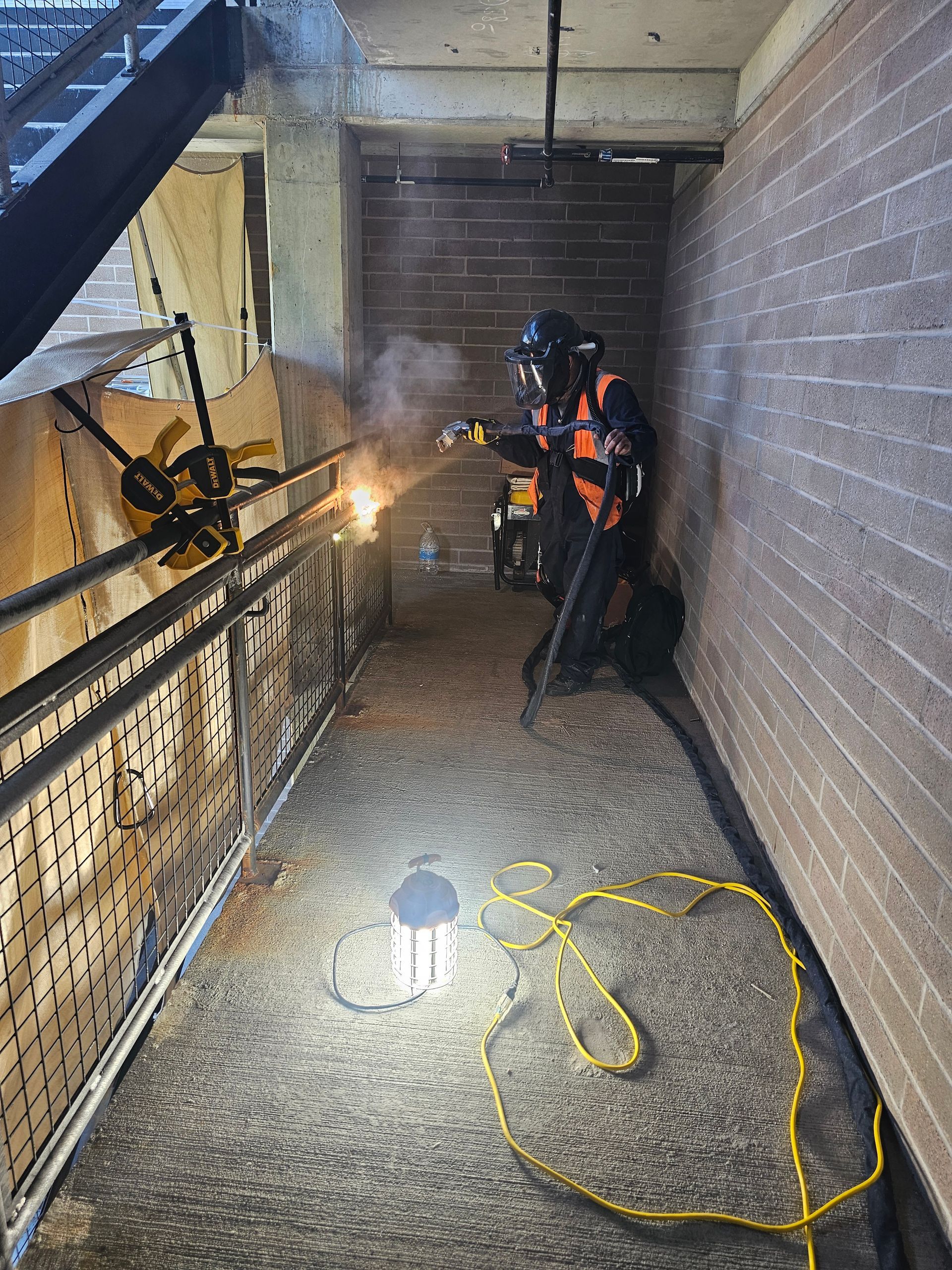 Worker in protective gear welding metal in a narrow hallway. Sparks fly.