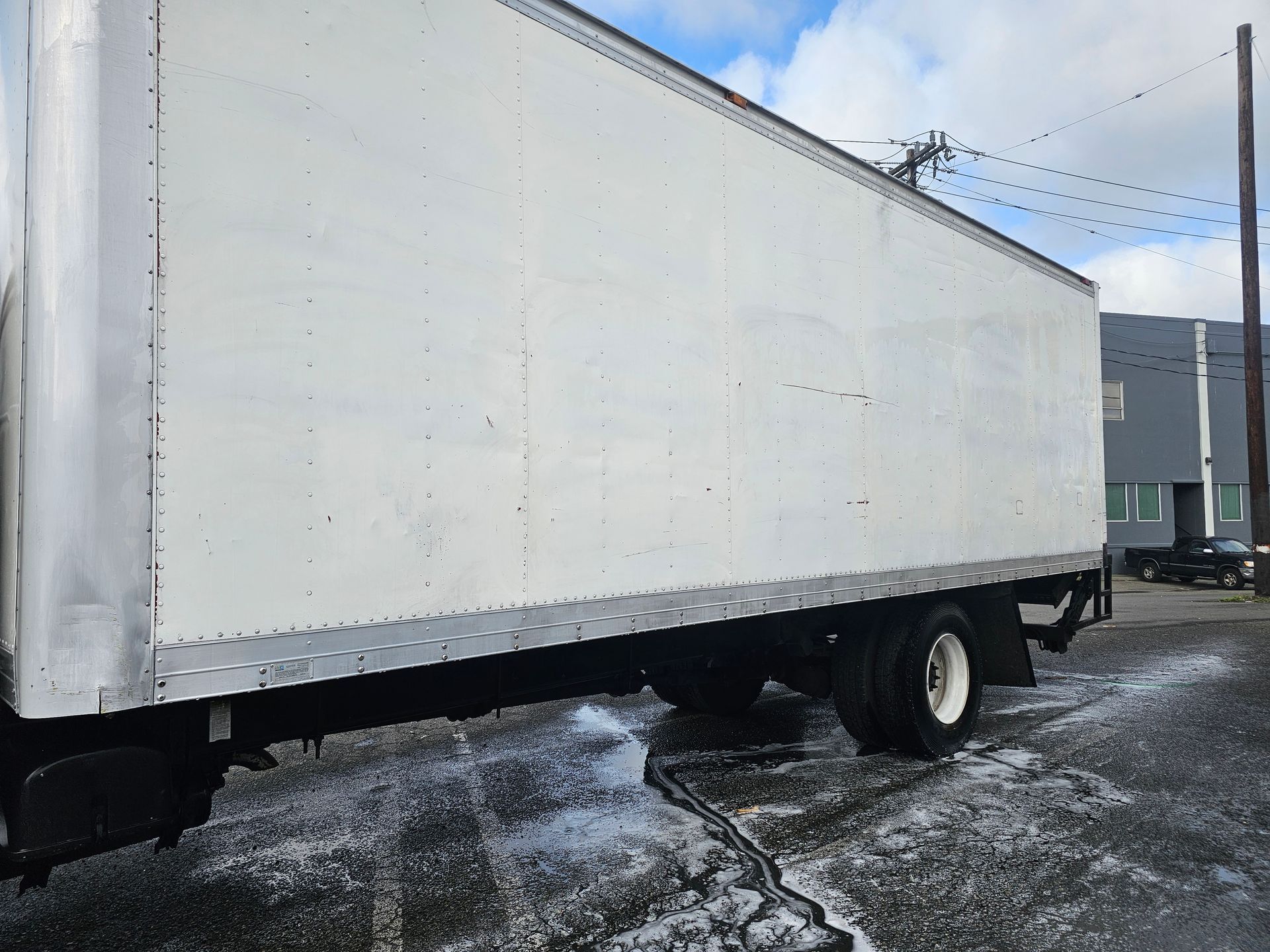 White box truck parked on a wet, paved surface.