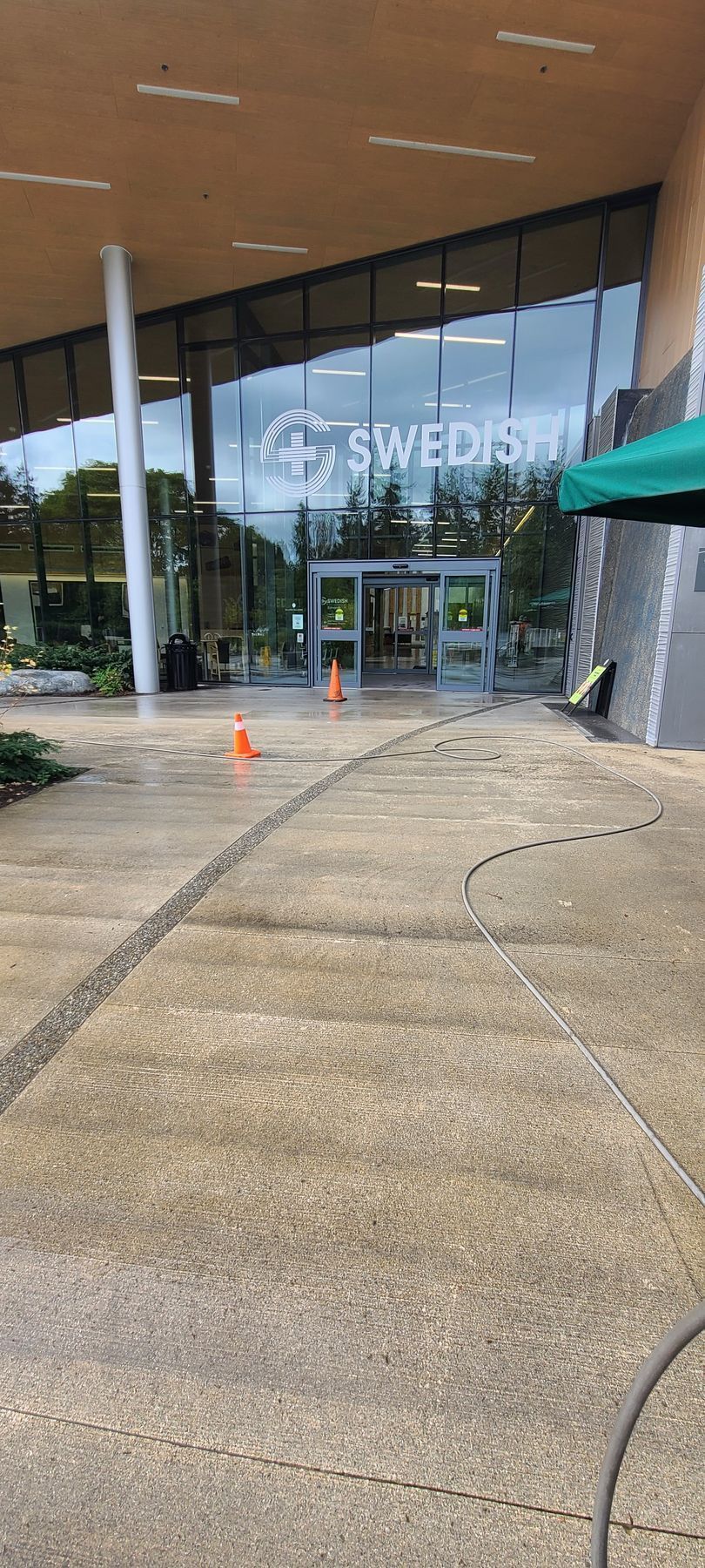 The entrance to the Swedish hospital, seen on a wet day with orange cones, and a coffee shop on the right.