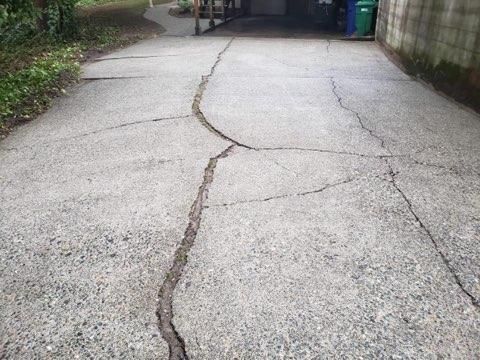 Cracked and damaged concrete driveway with large fissures running across the surface.